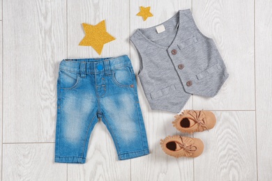 Flat lay composition with stylish child clothes and shoes on wooden background