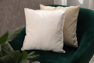 Photo of Soft pillows on green armchair in room