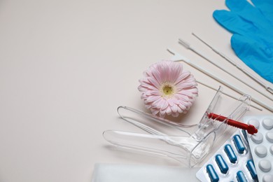 Gynecological tools, pills and gerbera flower on beige background, above view. Space for text