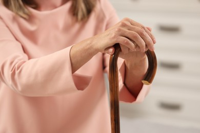 Photo of Mature woman with walking cane indoors, closeup