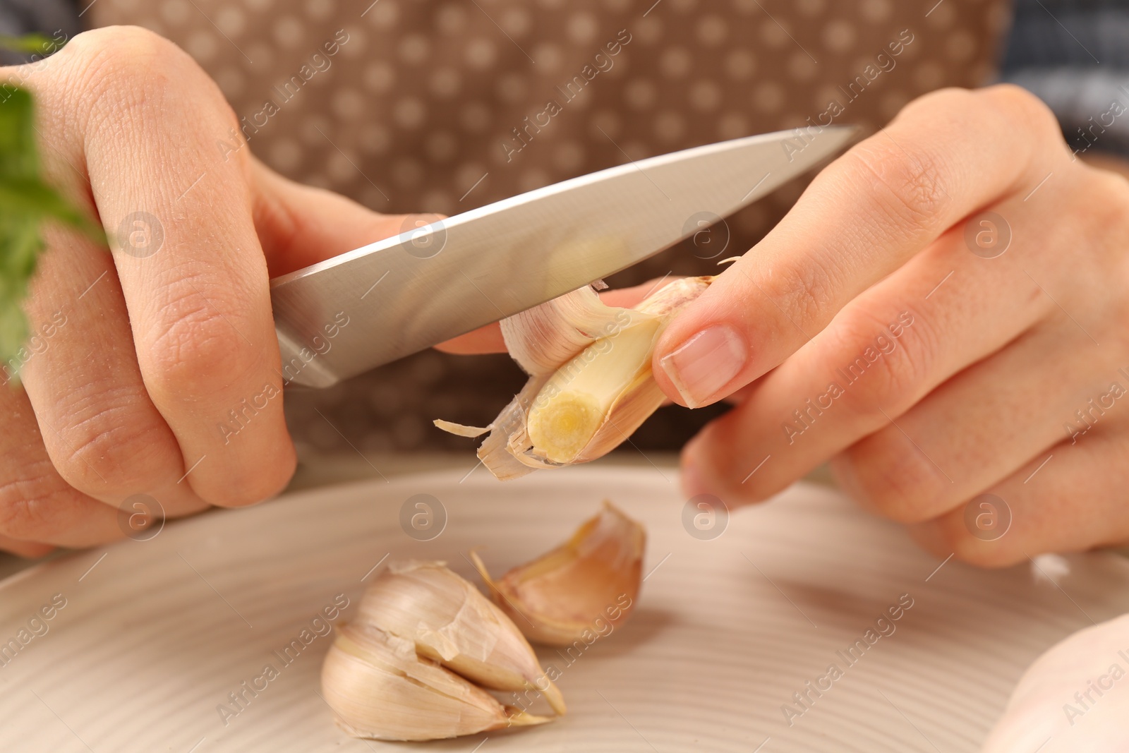 Photo of Woman peeling fresh garlic at table, closeup