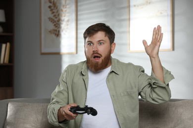 Surprised man with game controller at home