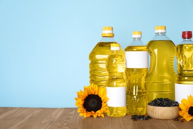 Photo of Bottles of cooking oil, sunflowers and seeds on wooden table, space for text