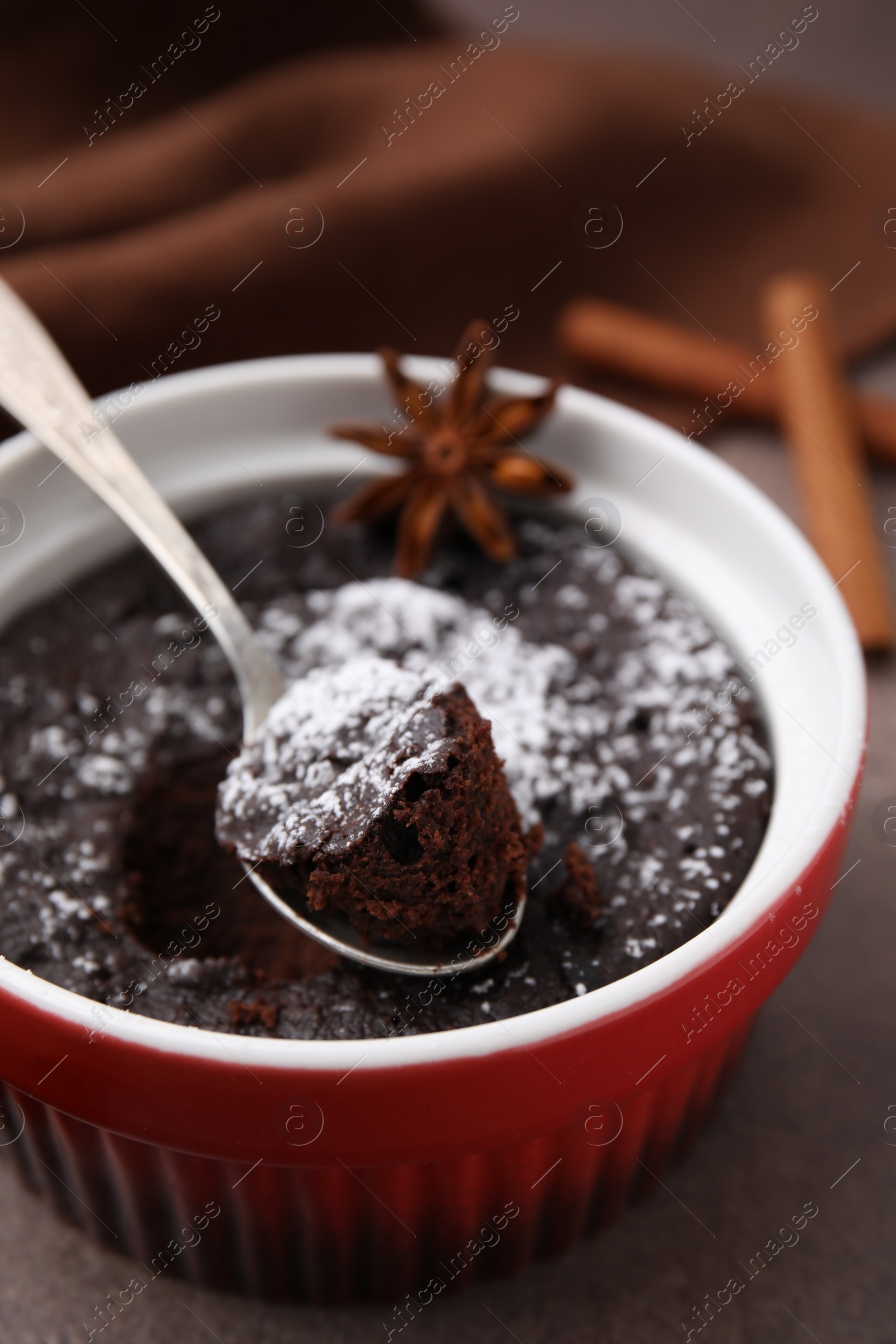 Photo of Tasty chocolate pie with anise and spoon on brown table, closeup. Microwave cake recipe