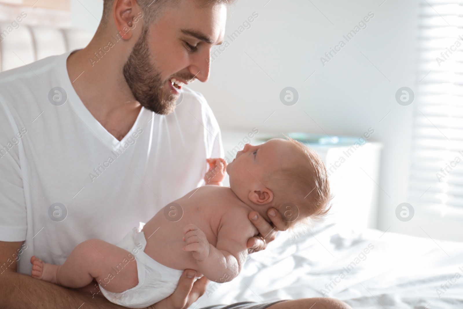 Photo of Father with his newborn son at home