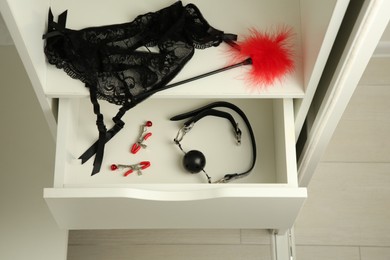 Photo of Nightstand with many different sex toys and garter belt indoors, above view