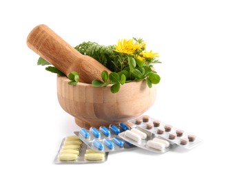 Photo of Mortar with fresh green herbs and pills on white background