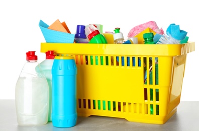 Photo of Shopping basket with different detergents on light grey marble table against white background