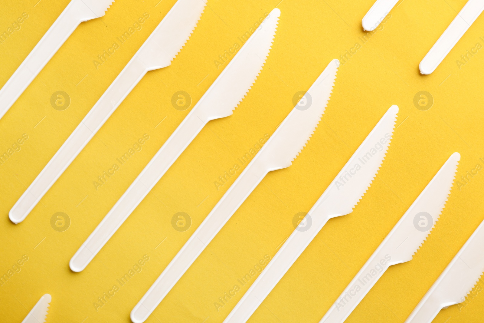 Photo of Plastic knives on color background, top view. Picnic table setting