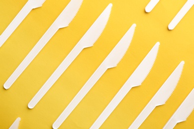 Plastic knives on color background, top view. Picnic table setting