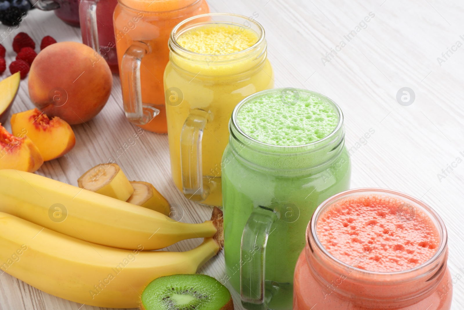 Photo of Many different tasty smoothies and ingredients on white wooden table, closeup