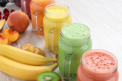 Photo of Many different tasty smoothies and ingredients on white wooden table, closeup