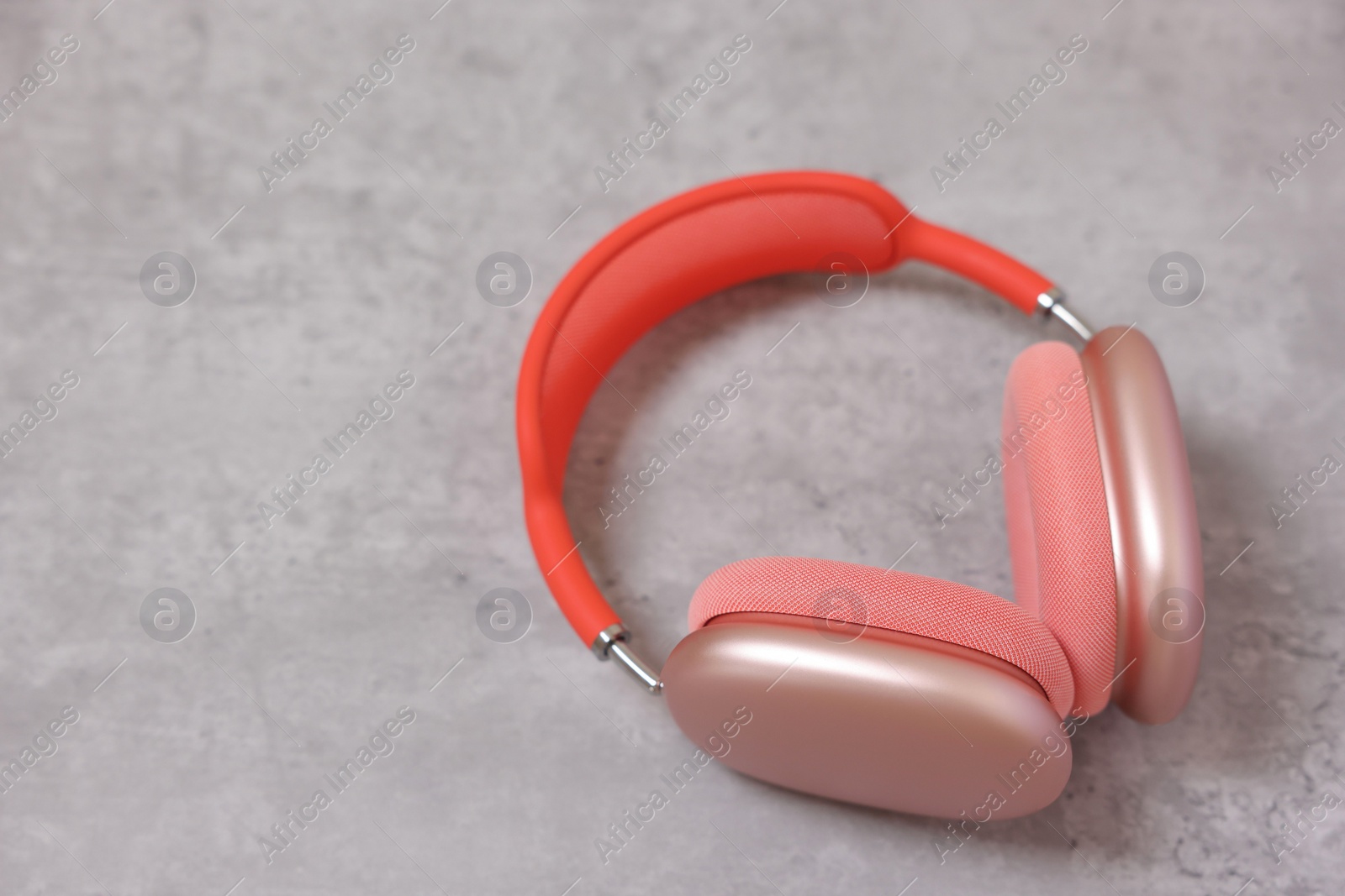 Photo of Stylish pink headphones on light grey table, closeup. Space for text