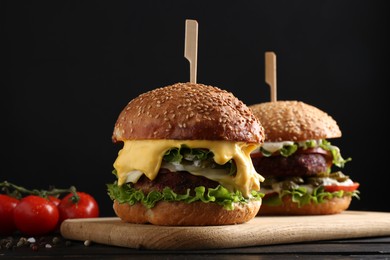 Photo of Vegetarian burgers with delicious patties on black wooden table, closeup