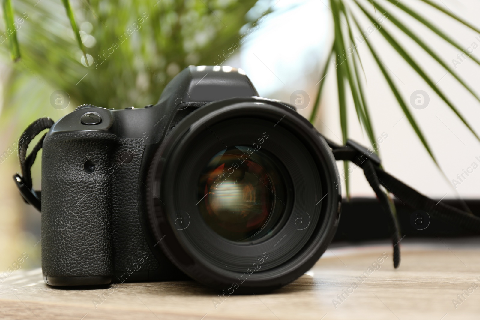Photo of Professional camera on table against blurred background. Photographer's equipment