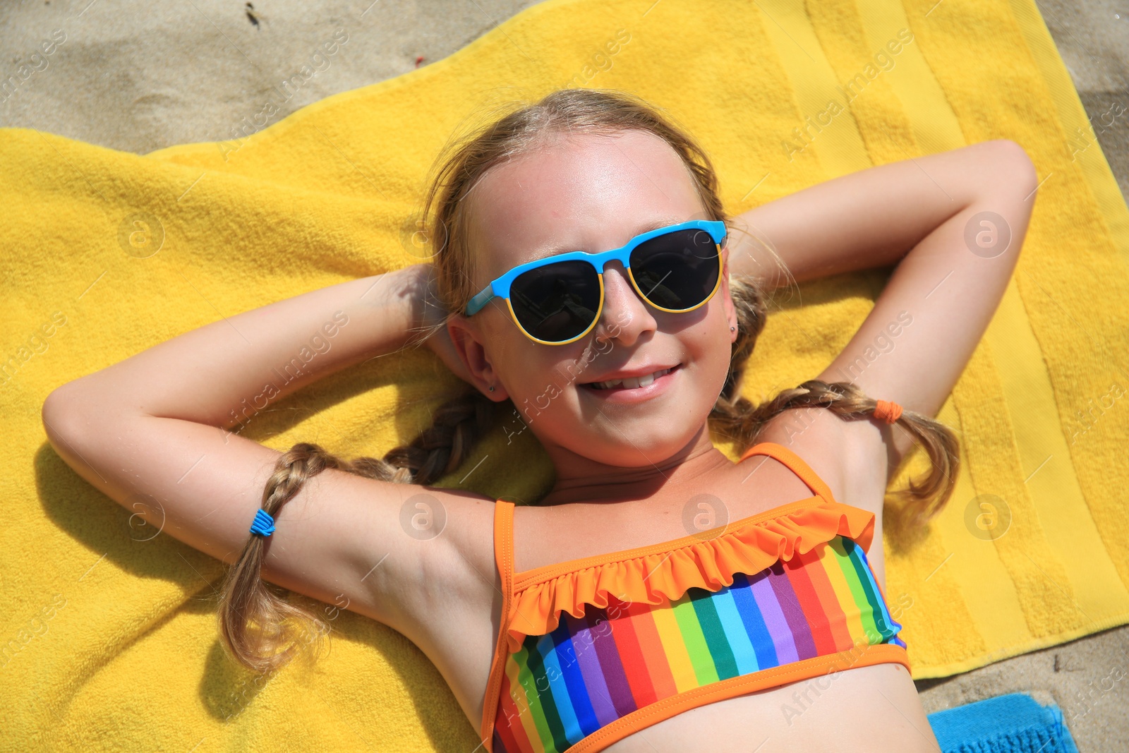 Photo of Happy little girl in sunglasses enjoying sunny day on sandy beach
