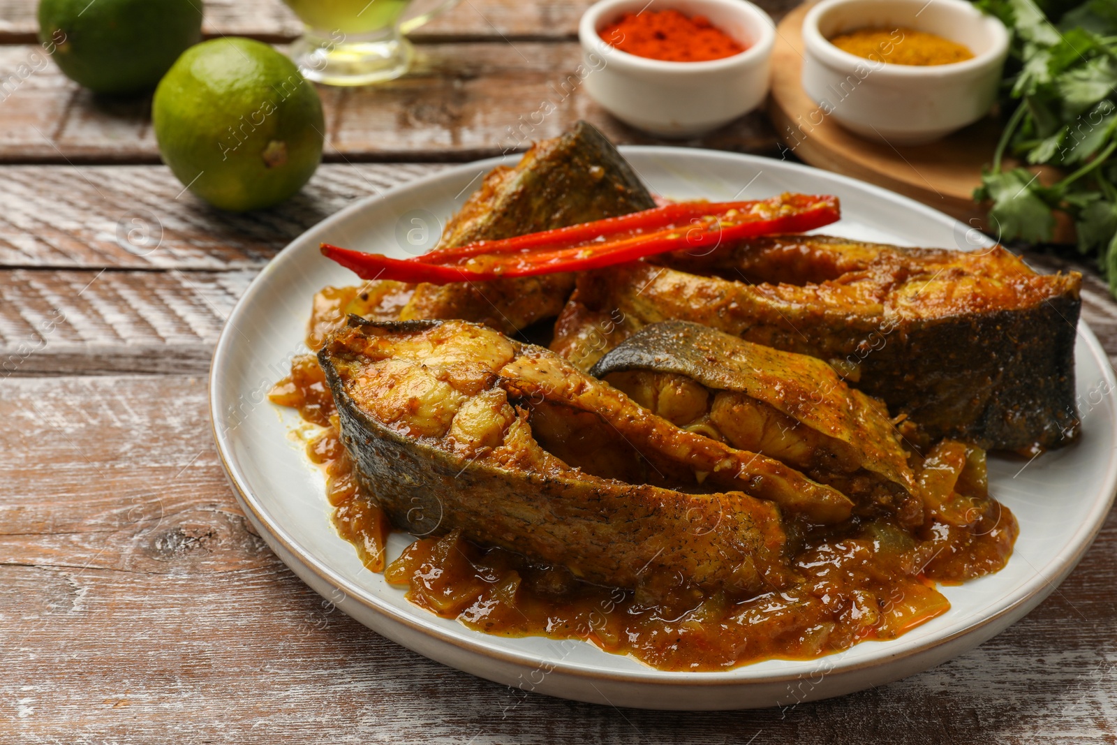 Photo of Tasty Indian fish curry on wooden table, closeup