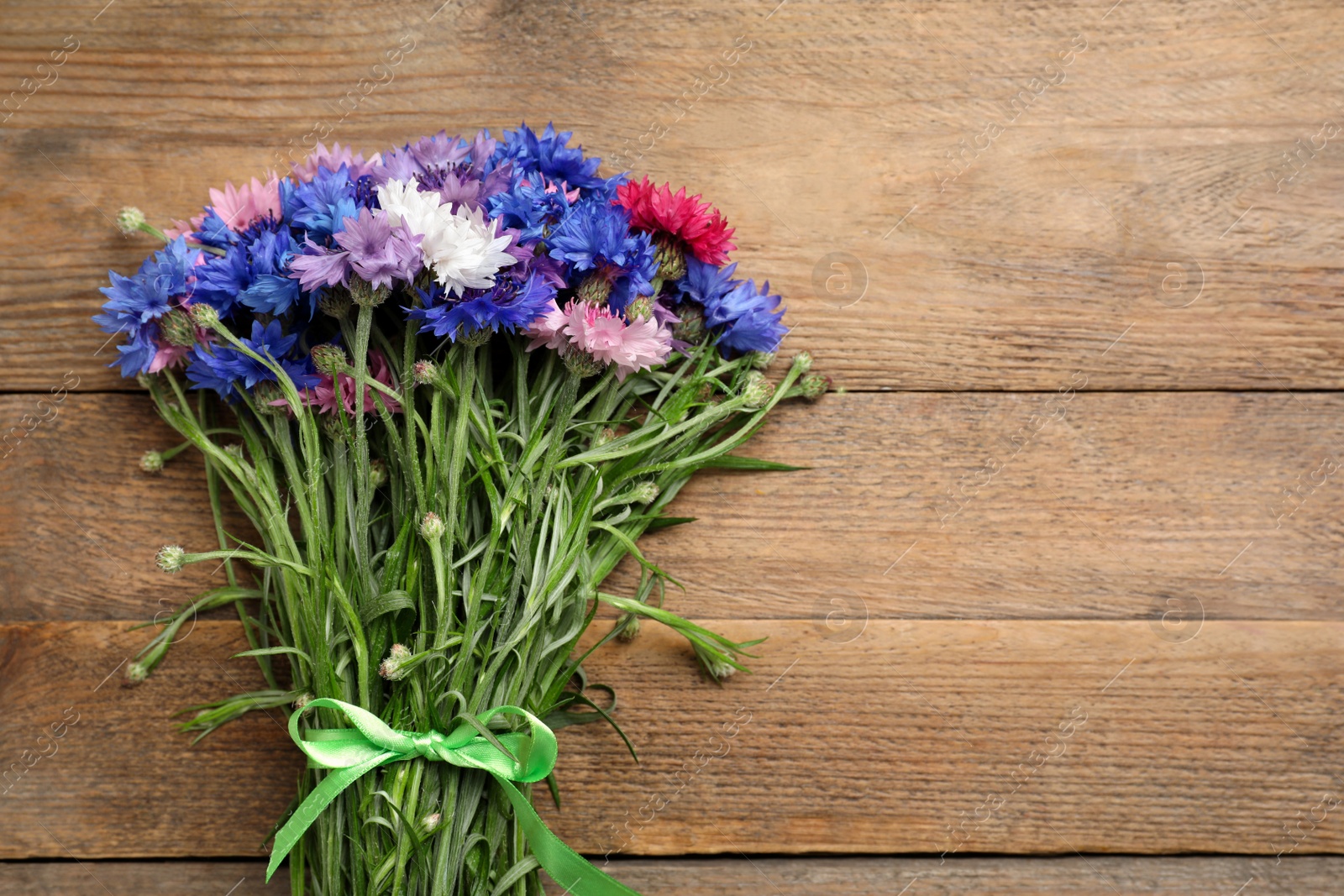 Photo of Bouquet of beautiful cornflowers on wooden table, top view. Space for text