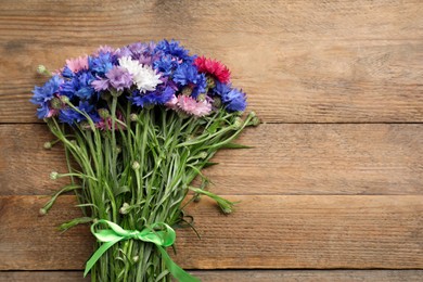 Photo of Bouquet of beautiful cornflowers on wooden table, top view. Space for text