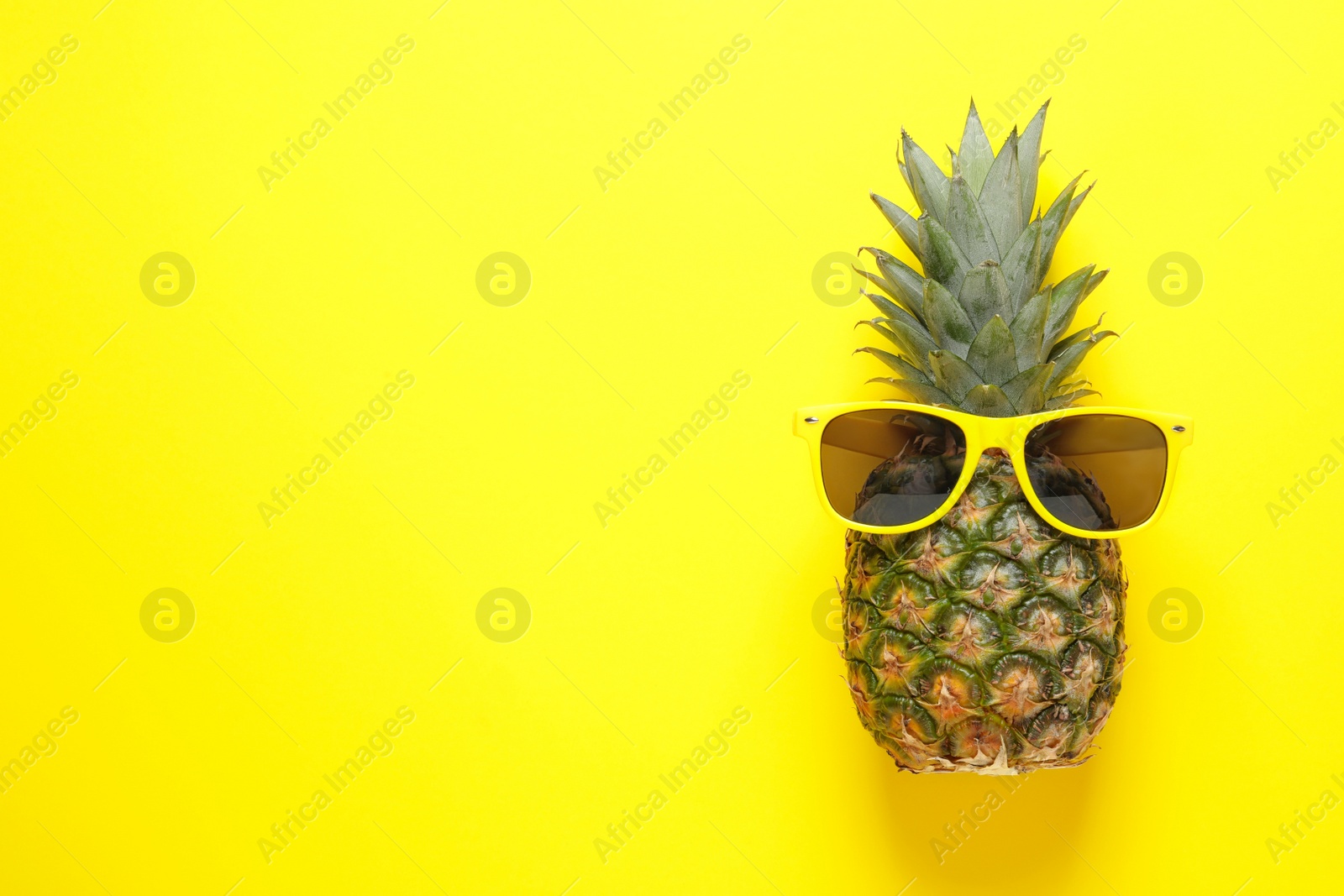 Photo of Pineapple and sunglasses on color background, top view with space for text. Beach accessories