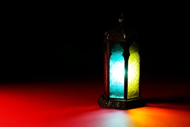 Decorative Arabic lantern on table against dark background. Space for text