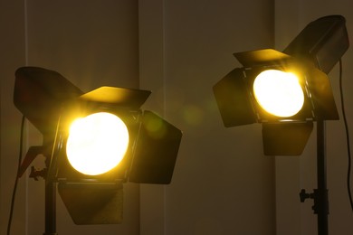 Photo of Bright yellow spotlights near wall indoors. Professional stage equipment