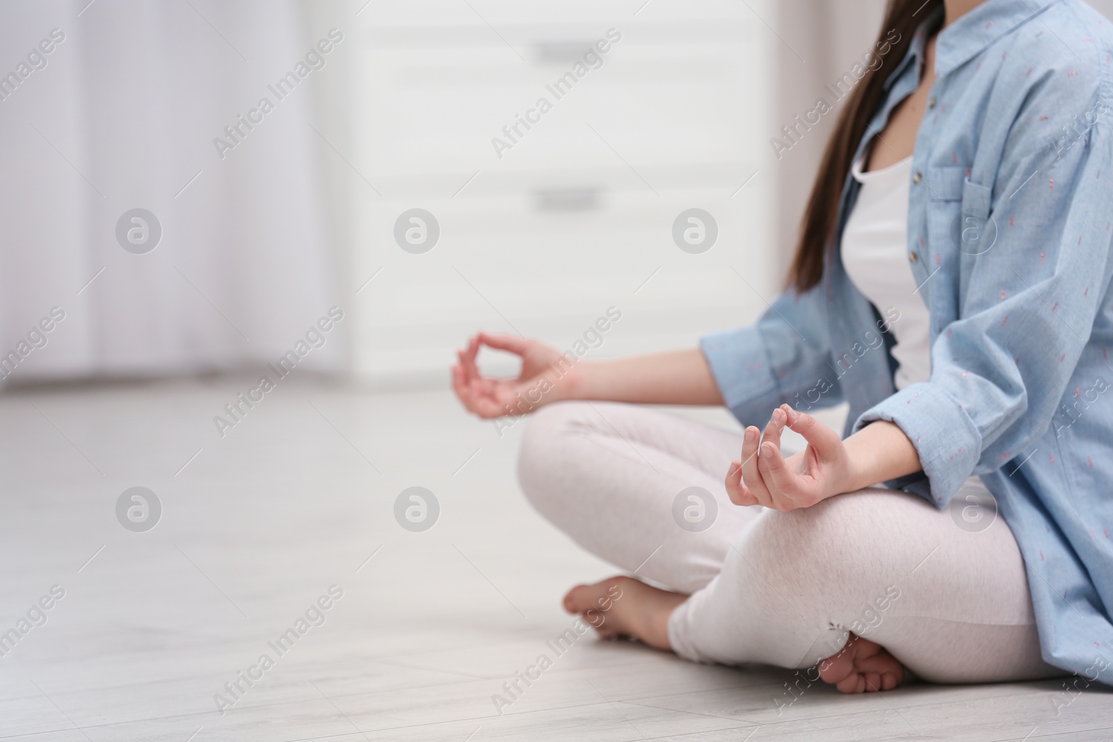 Photo of Young woman meditating on floor at home, closeup with space for text. Zen concept