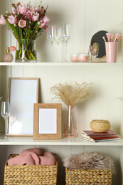 Photo of White shelving unit with glassware and different decorative elements