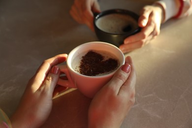 Photo of Women with cups of hot coffee at grey table, closeup