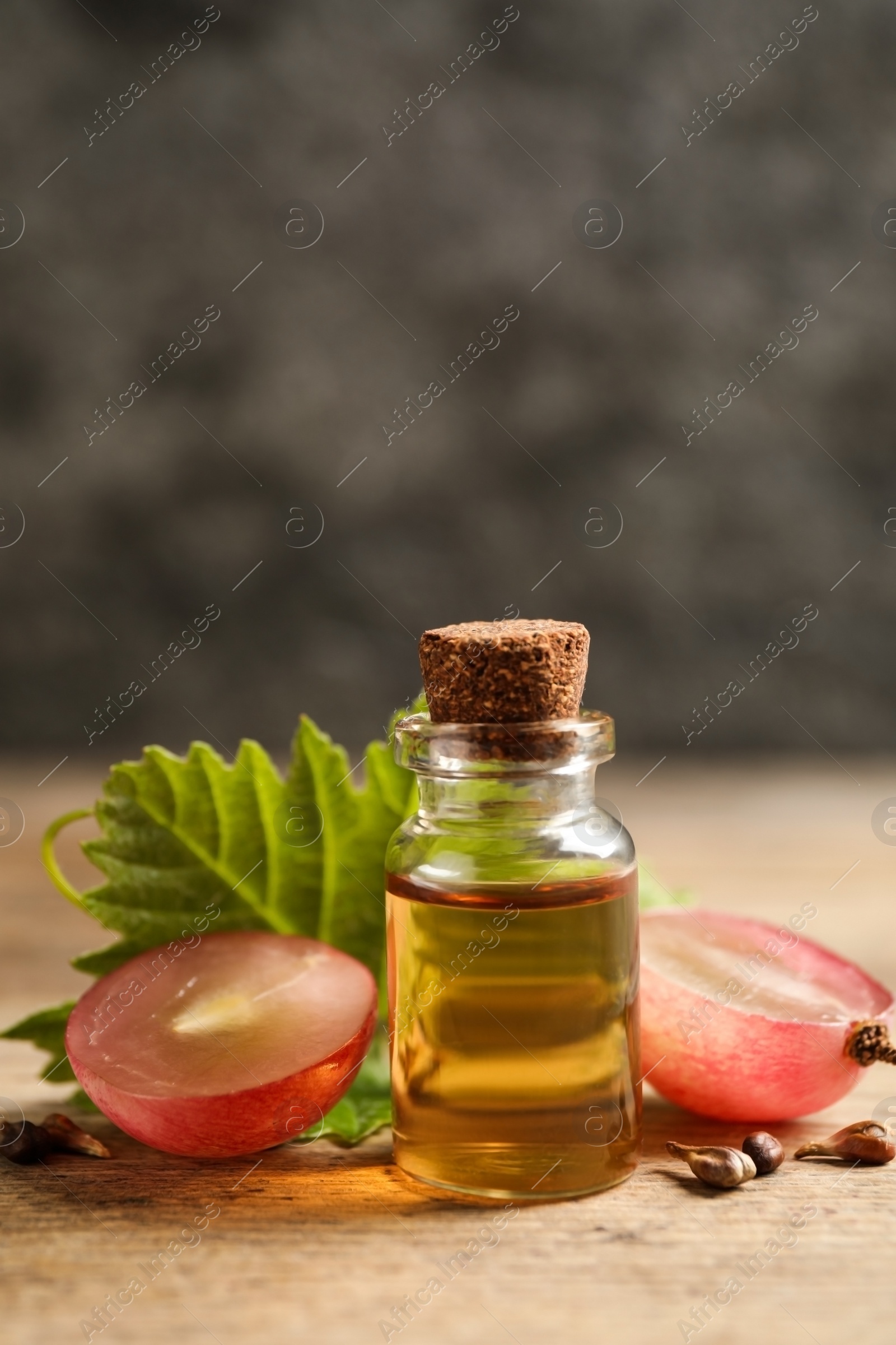 Photo of Bottle of natural grape seed oil on wooden table. Organic cosmetic