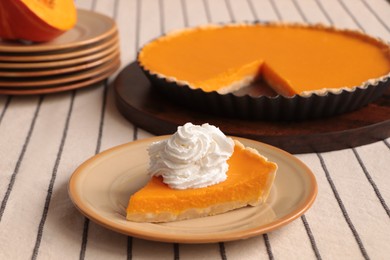 Piece of fresh homemade pumpkin pie with whipped cream on table