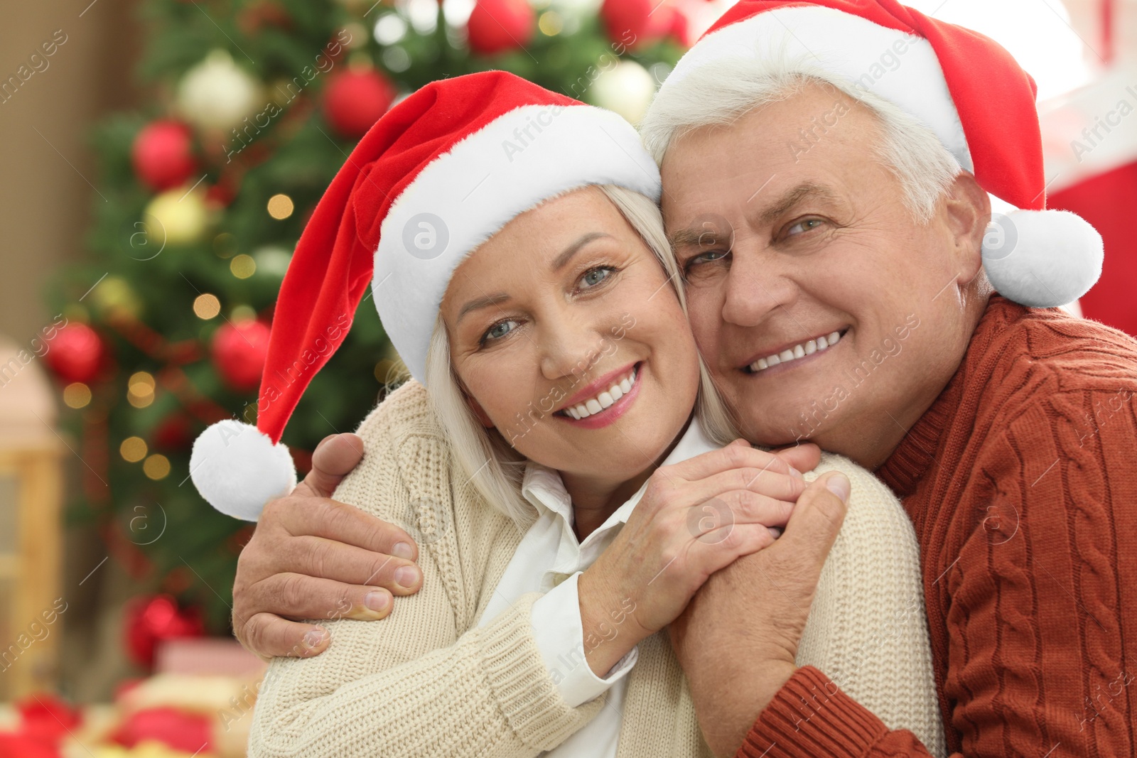 Photo of Happy mature couple in Santa hats at home. Christmas celebration