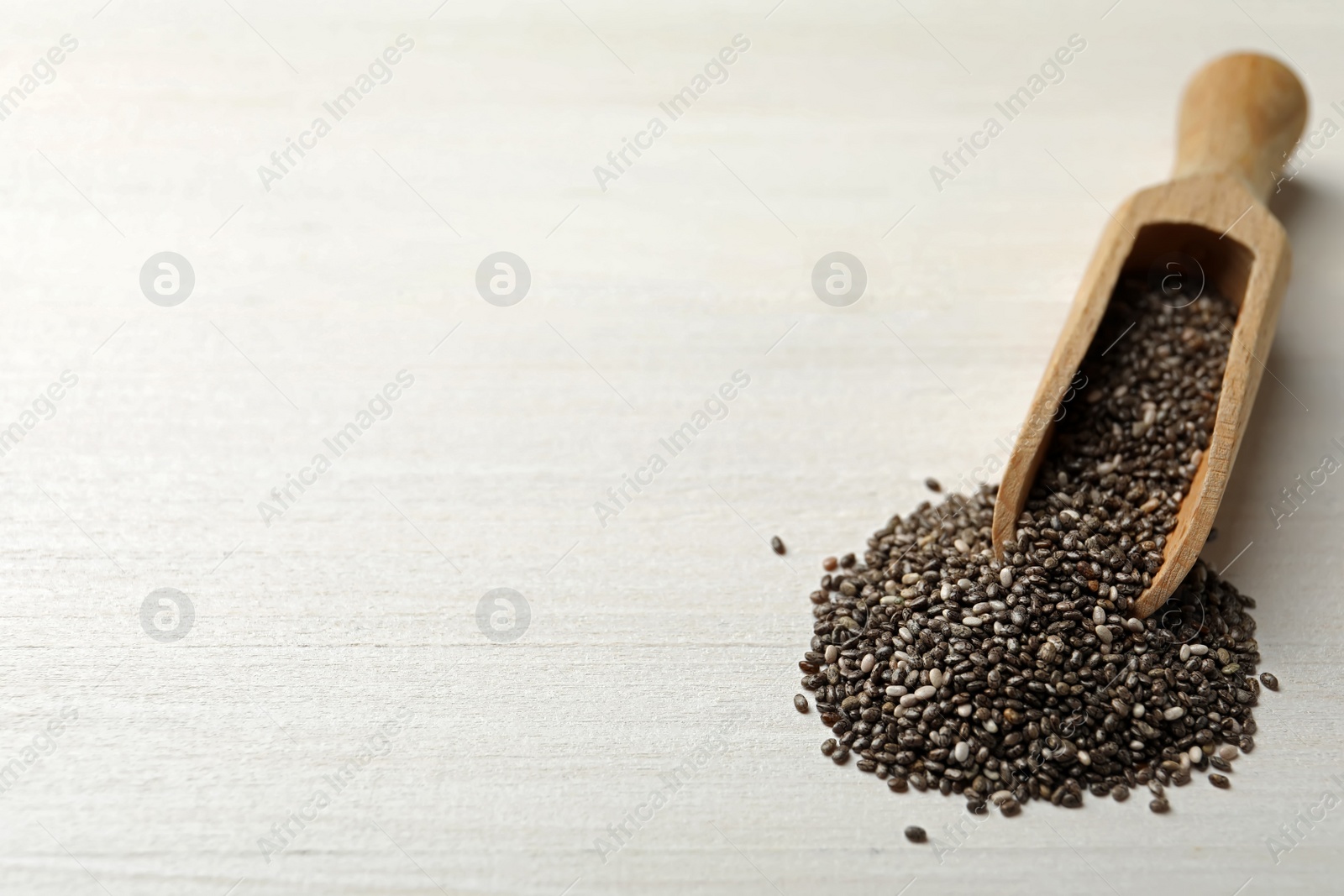 Photo of Scoop with chia seeds on white wooden table. Space for text