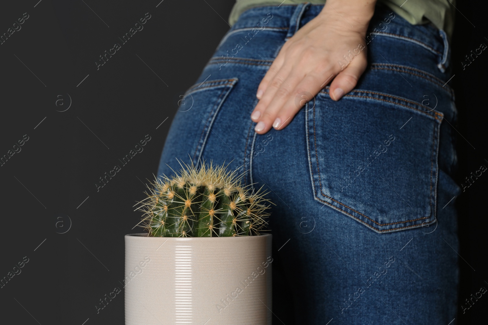 Photo of Woman sitting down on cactus against black background, closeup. Hemorrhoid concept