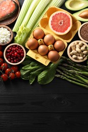 Many different healthy food on black wooden table, flat lay. Space for text