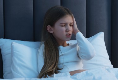 Little girl suffering from headache in bed at night