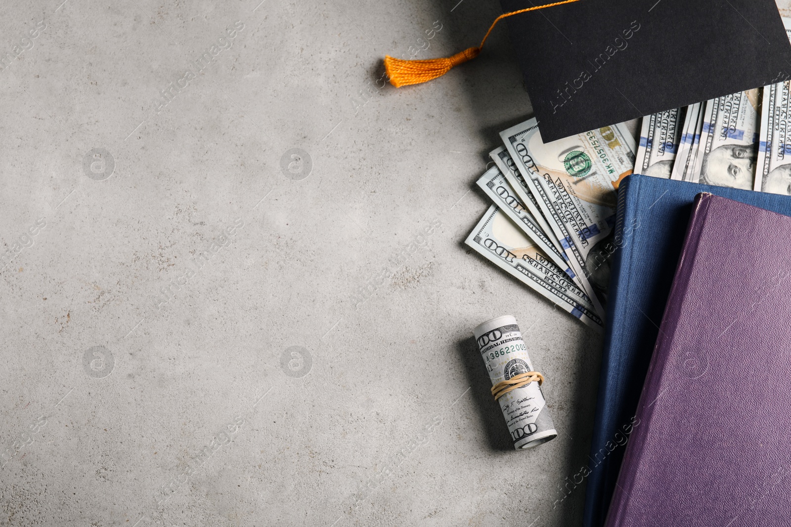 Photo of Flat lay composition with dollars and student graduation hat on stone background, space for text. Tuition fees concept