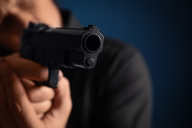 Man holding gun on dark blue background, focus on barrel