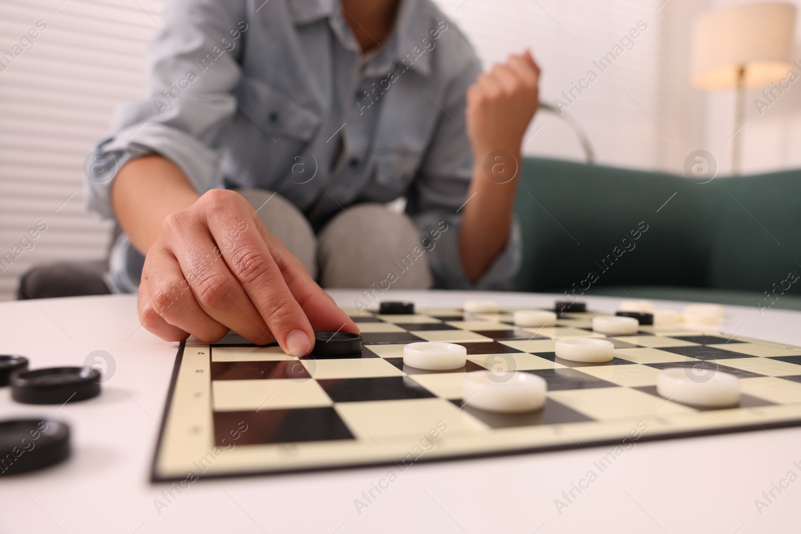 Photo of Woman enjoying playing checkers at home, closeup