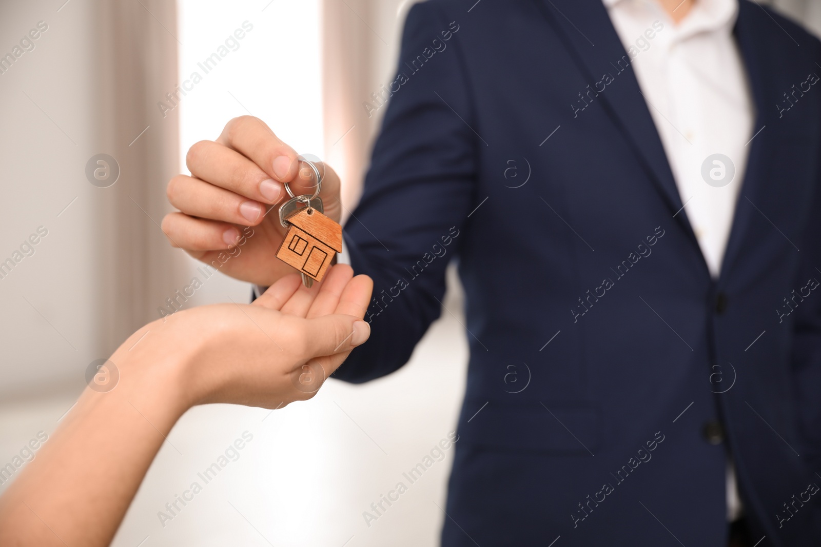 Photo of Real estate agent giving key with trinket to client in office, closeup