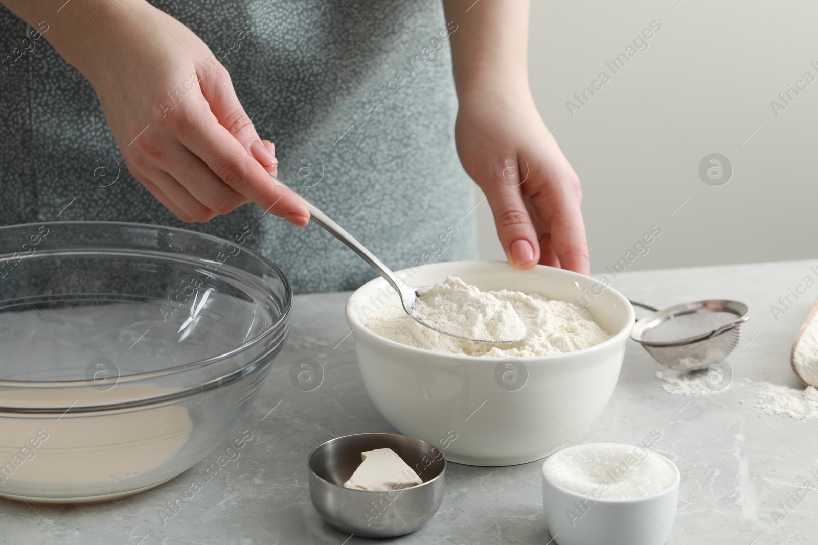 Photo of Woman making dough for traditional grissini at light grey marble table indoors, closeup