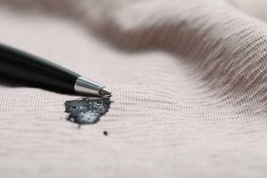 Photo of Pen and stain of black ink on beige shirt, closeup. Space for text