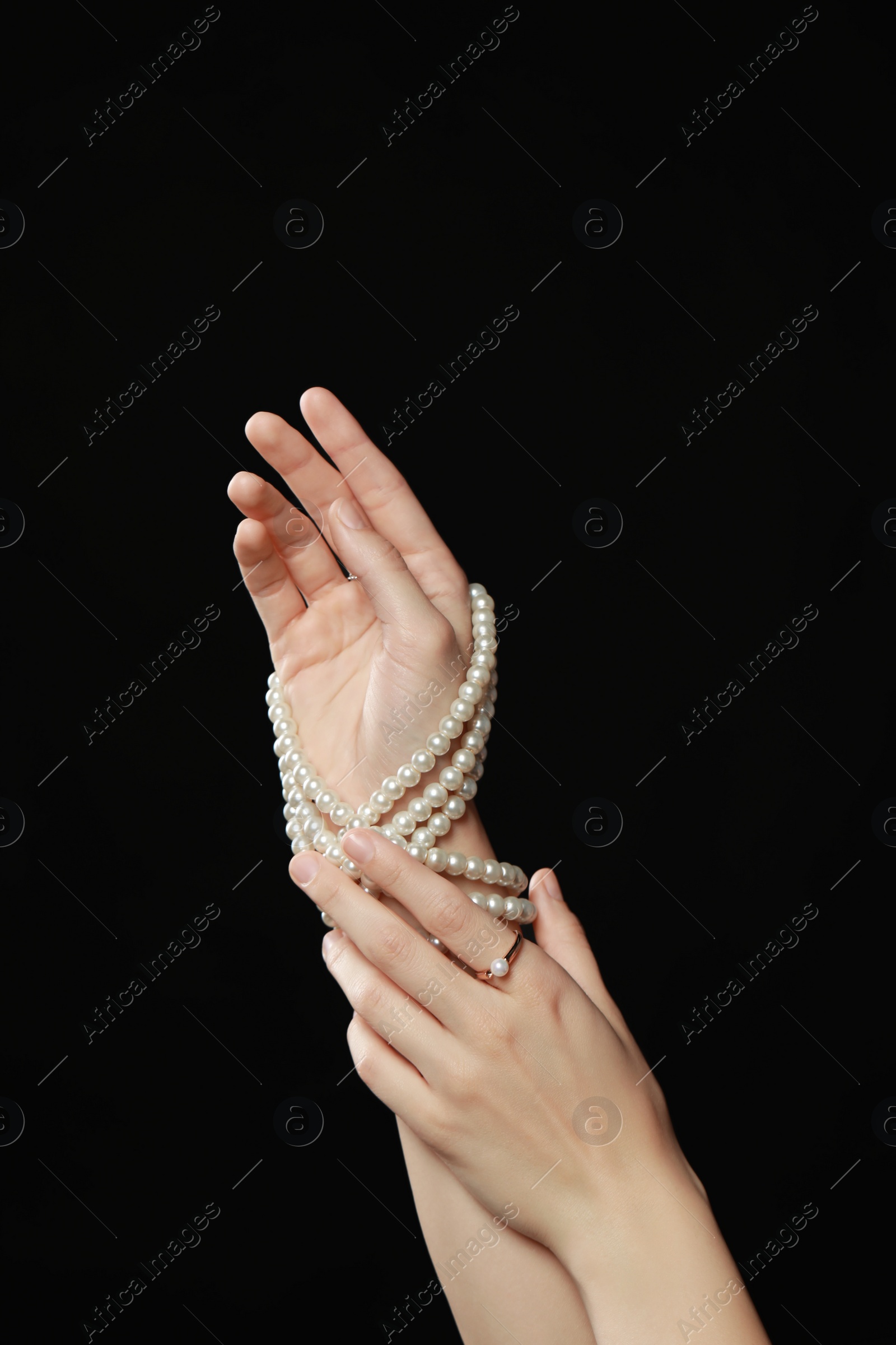 Photo of Young woman with elegant pearl jewelry on black background, closeup