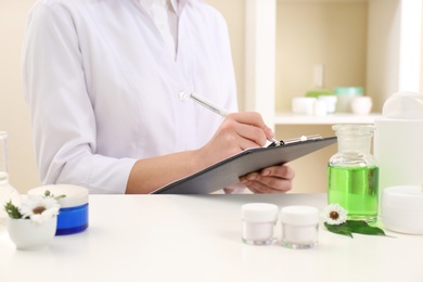 Photo of Female dermatologist doing research for new skin care product at table, closeup