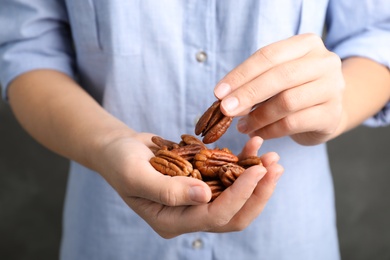 Photo of Woman holding shelled pecan nuts in hands, closeup