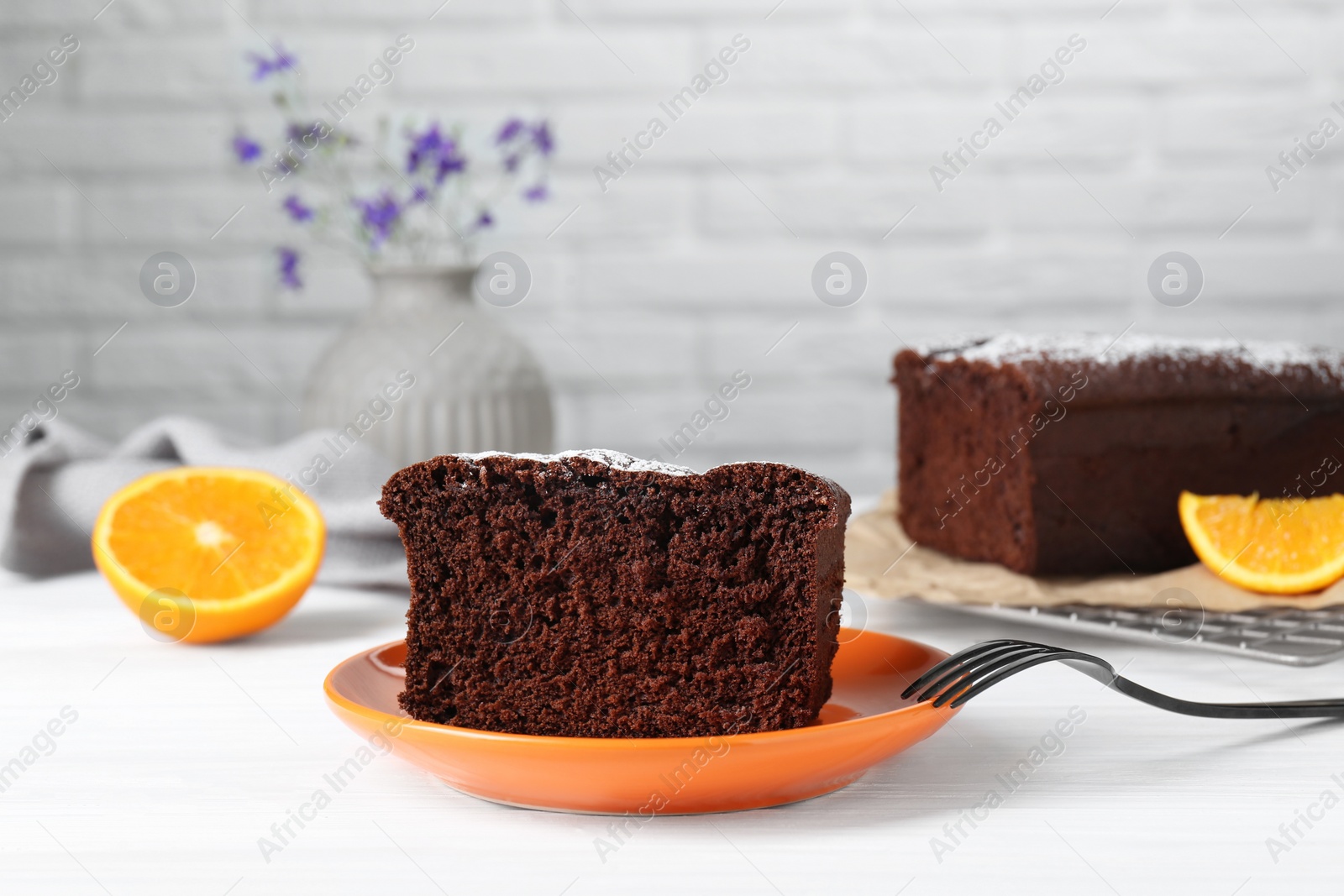 Photo of Piece of tasty chocolate sponge cake with powdered sugar on white table