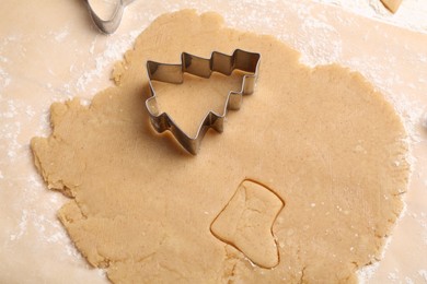 Photo of Raw dough and cookie cutter in shape of Christmas tree on table