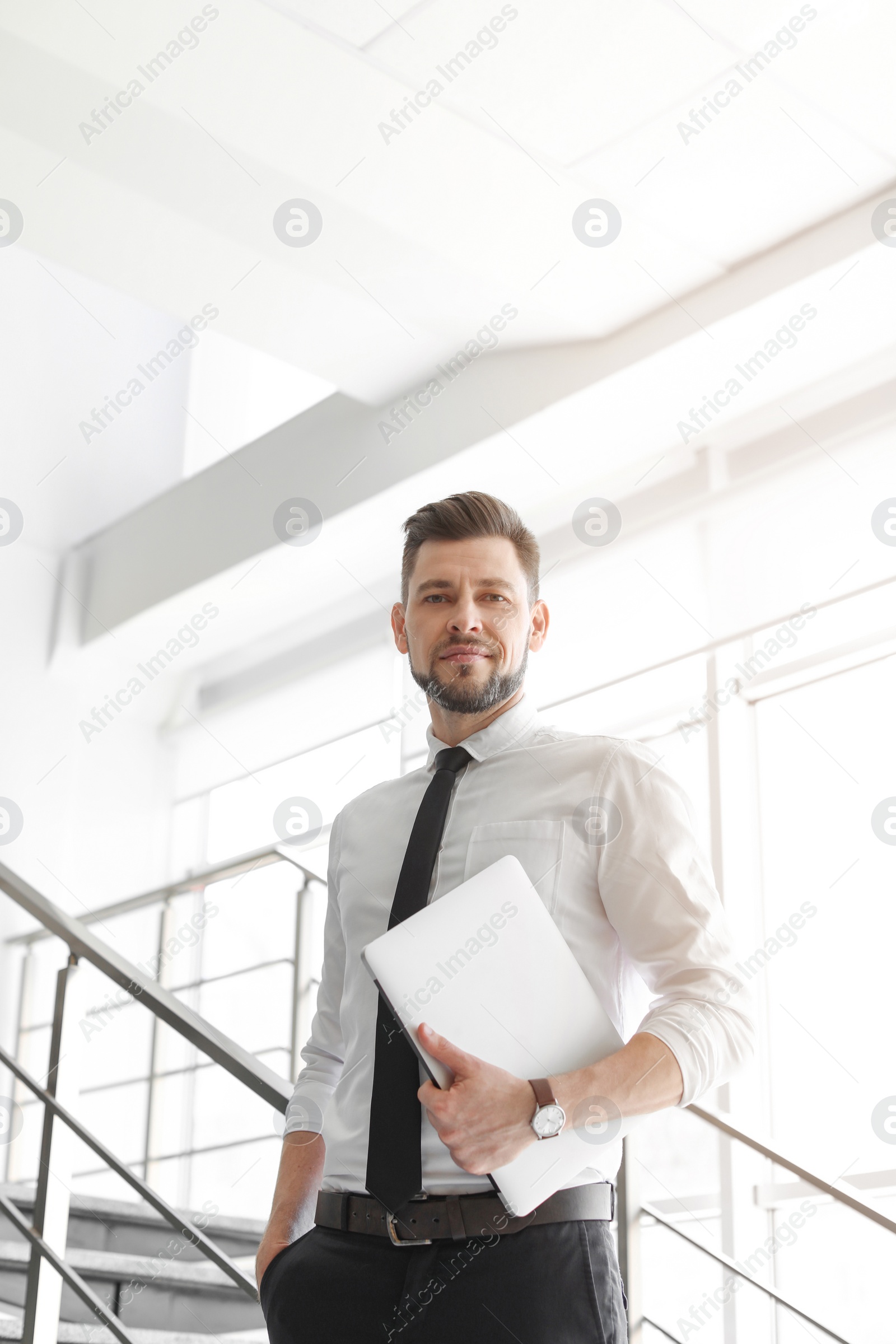 Photo of Male lawyer with laptop near stairs in office