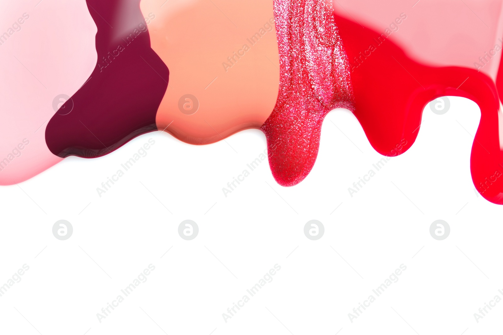 Photo of Colorful nail polishes spilled on white background