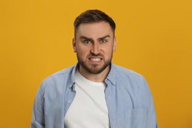 Photo of Angry young man on yellow background. Hate concept